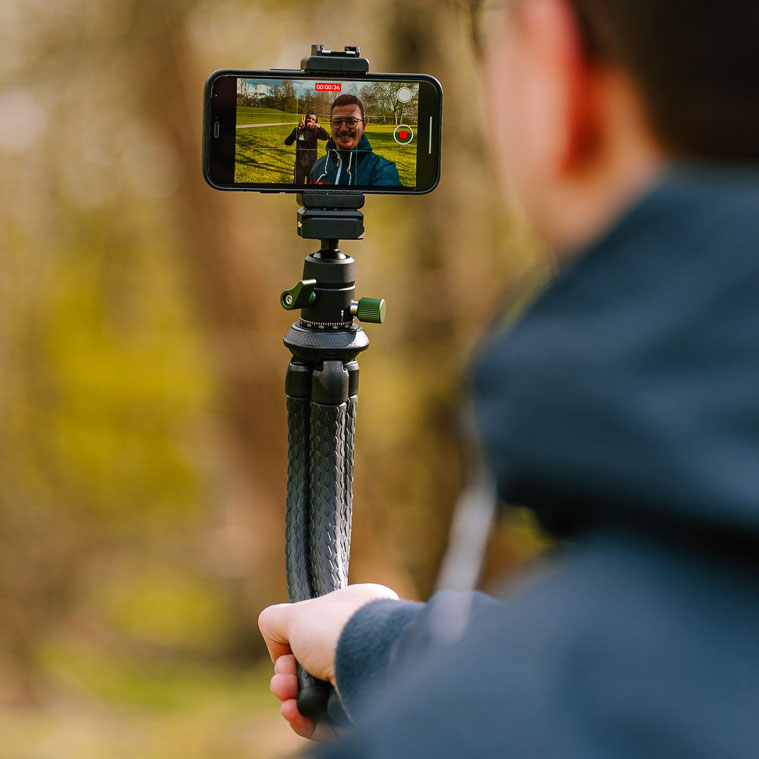 Abgebildet ist eine Person, die mithilfe des Creatorpod Stativs ein Handy-Selfie macht.