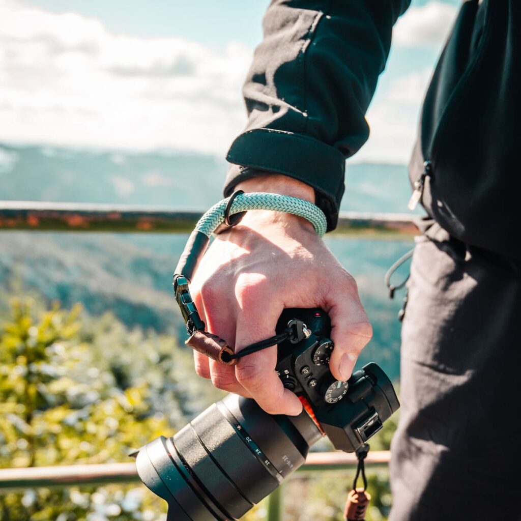 Mann trägt Kamerahandschlaufe aus Kletterseil in der Natur in der Farbe mighty mint