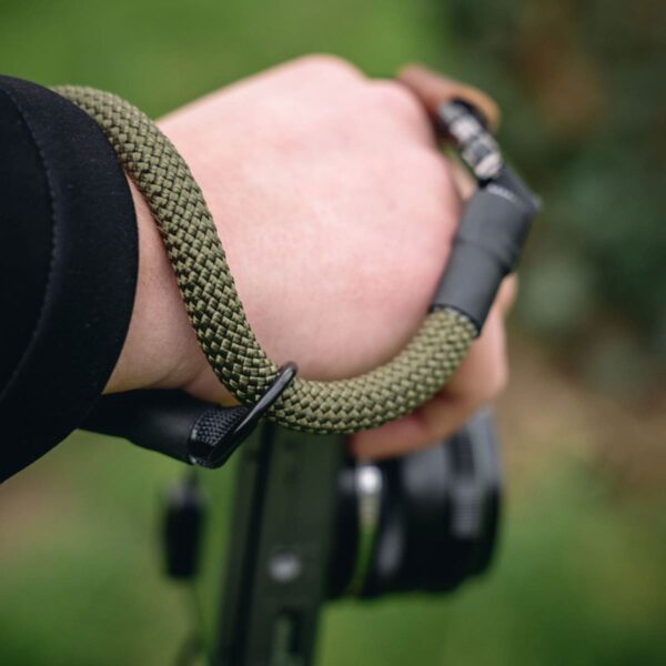 Mann trägt Kamerahandschlaufe aus Kletterseil in der Natur in der Farbe military olive
