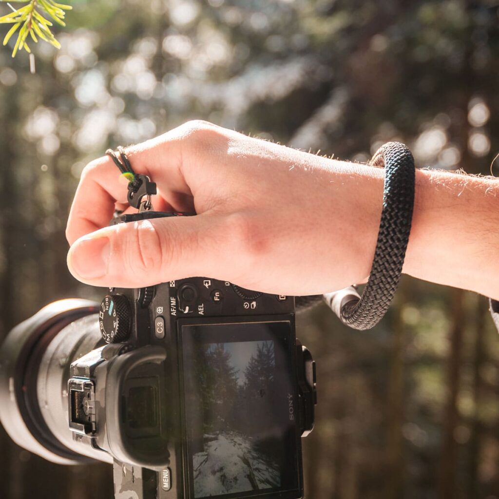Mann trägt Kamerahandschlaufe aus Kletterseil in der Natur in der Farbe silent black