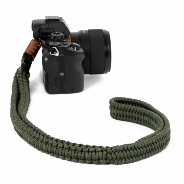 Hier sieht man eine Kamera, an der der Traveler Kameragurt der Farbe Military Olive von C-Rope mit dem Schnellerschluss befestigt ist.