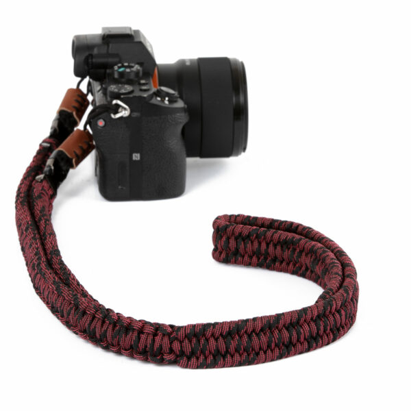 Auf dem Bild abgebildet ist eine Kamera mit dem C-Rope Kameragurt The Traveler in der Farbe Red Dots.